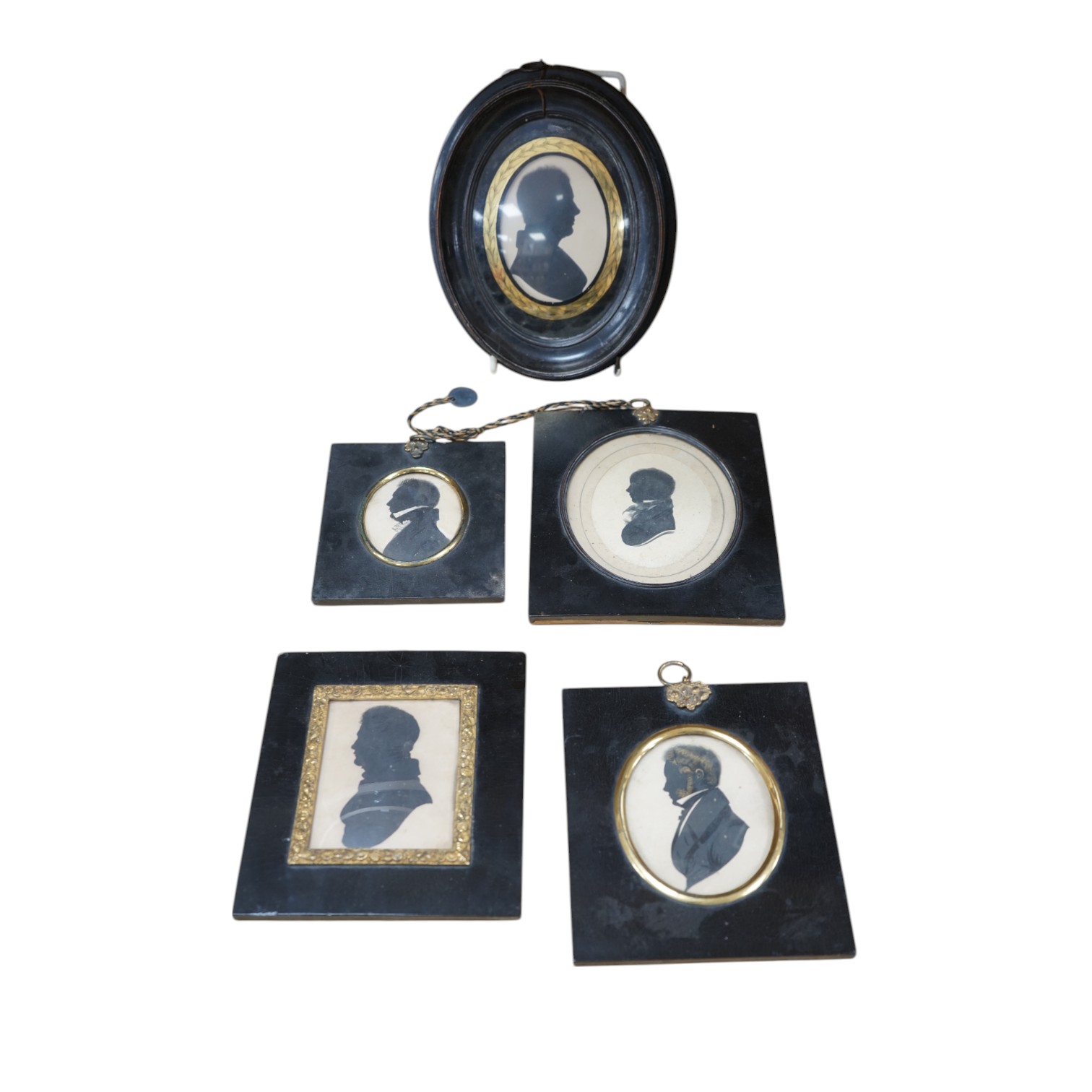 A family group of five 19th century silhouettes in ebony frames, largest 9cm high. Condition - fair